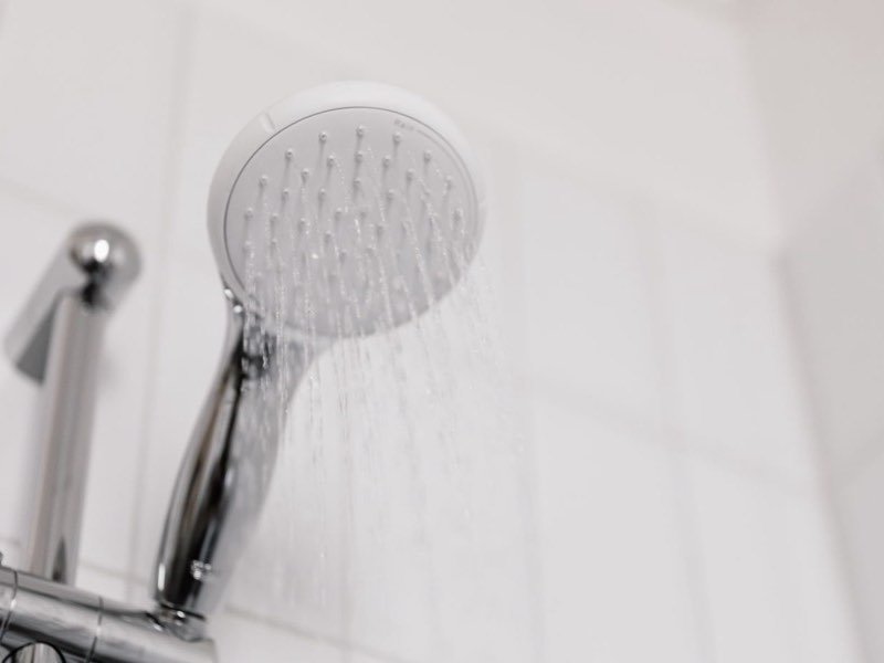 Regadera con poca presión de agua caliente en un baño